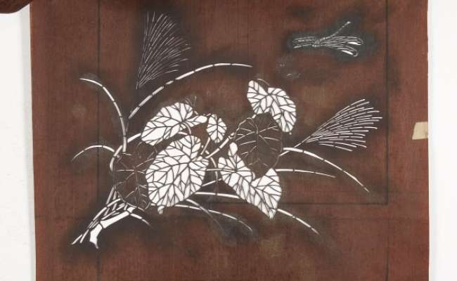 Three katagami stencils which together form a design of a flowering plant and a grass  with a dragonfly nearby