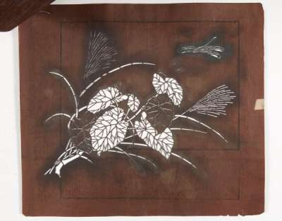 Three katagami stencils which together form a design of a flowering plant and a grass  with a dragonfly nearby