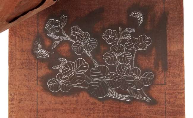 Three katagami stencils which together form a design of flowering stems with two  butterflies around the flowers