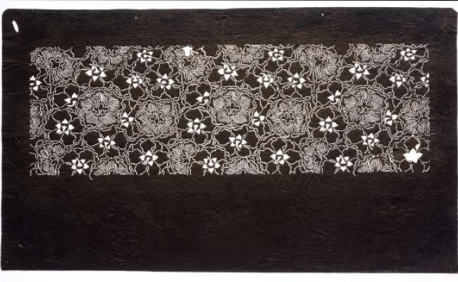 Katagami stencil with an all-over pattern of flowers, possibly peonies, shown from behind.