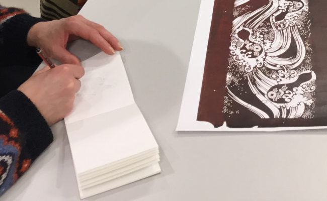 drawing in a notebook looking at a katagami stencil